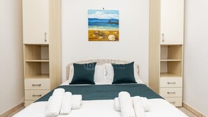 A hotel room with a bed, two bedside tables, a painting of a beach scene, and a pair of towels on the bed. - SALENTINE DAYS - 3 (Torre Lapillo)