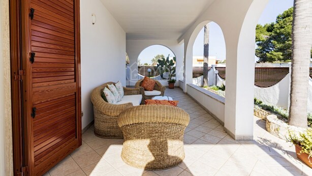 A covered outdoor seating area with wicker furniture, a wooden door, and arched ceilings. - SALENTINE DAYS - 3 (Torre Lapillo)