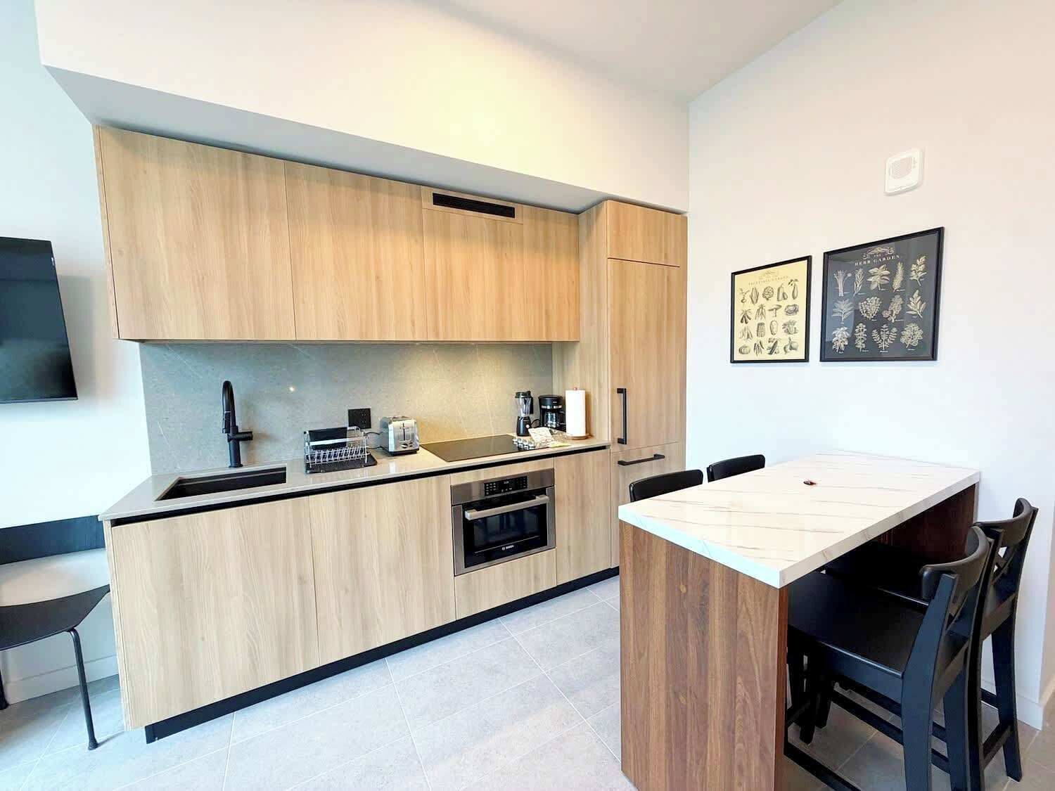 A modern kitchen with wooden cabinets, a built-in oven, and a dining area with a table and chairs.
