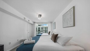 Et hotelværelse med en stor seng, et trænatbord, et billedværk på væggen og udsigt ud