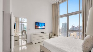 A modern hotel room with a large bed, a flat-screen TV, a dresser, and a view of the cityscape. - Icon Brickell 2BDR 40th Fl Ocean Views+Spa Access (Miami)