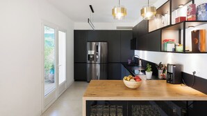 A modern kitchen with a large refrigerator, a wooden countertop, and a built-in wine rack. - 🌿 Villa Familiale à Quelques Pas du Vieux Mougins (Mougins)