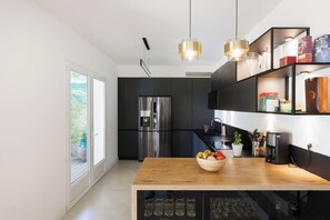 Eine moderne Küche mit einem großen Kühlschrank, einer Holz Arbeitsplatte und einem integrierten Weinkühlschrank.