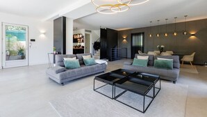A modern living room with two grey sofas, a black coffee table, and a staircase leading to an upper level. - 🌿 Villa Familiale à Quelques Pas du Vieux Mougins (Mougins)