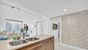Una cocina moderna con una isla grande, pileta de acero inoxidable y muebles de madera.