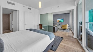 Ein modernes Hotelzimmer mit einem großen Bett, einem Schreibtisch, einem Sessel und einem Fernseher.