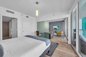Ein modernes Hotelzimmer mit einem großen Bett, einem Schreibtisch, einem Sessel und einem Fernseher.