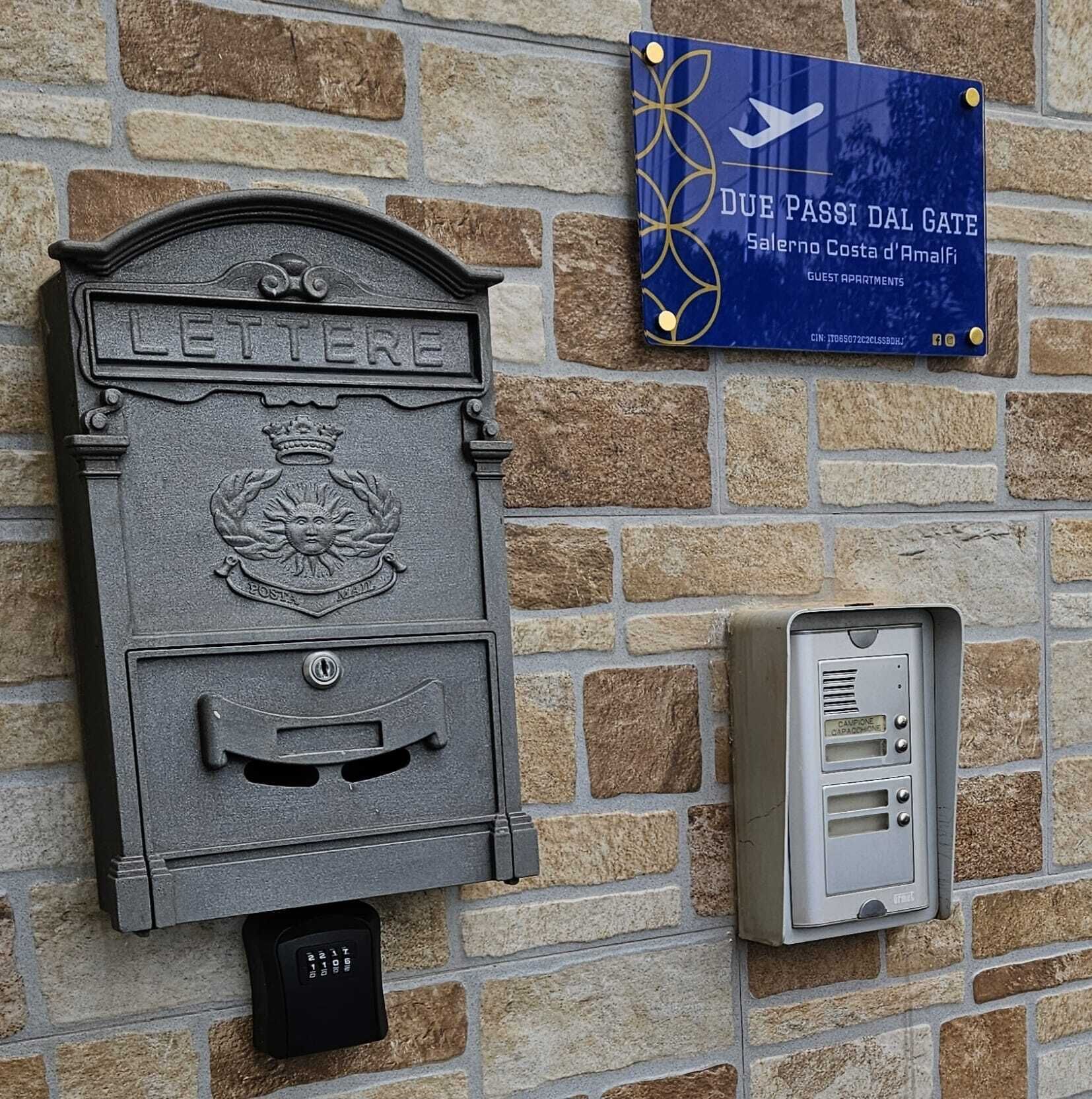 A mailbox labeled 'LETTERE' and a blue sign with 'DUE PASSI DAL GATE' on a stone wall.