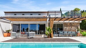 Ein Poolbereich mit Pergola, Sitzmöbeln im Freien und Blick auf den Pool.