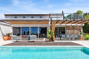 Ein Poolbereich mit Pergola, Sitzmöbeln im Freien und Blick auf den Pool.