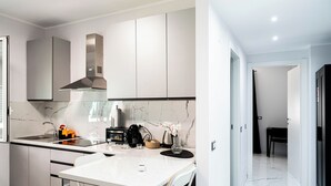 A modern kitchen with a marble countertop, stainless steel appliances, and a dining area with a white table and chairs. - Oasis of Peace in the Middle of Town: Modern, Quiet and Close to Transportation (Genova)
