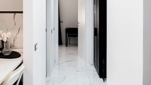 A hallway with white walls, a marble floor, and a dining area in the distance. - Oasis of Peace in the Middle of Town: Modern, Quiet and Close to Transportation (Genova)