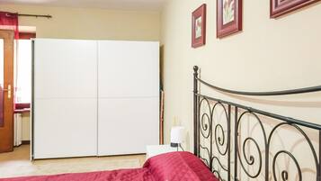 A bedroom with a bed, a wardrobe, a nightstand, and a lamp.