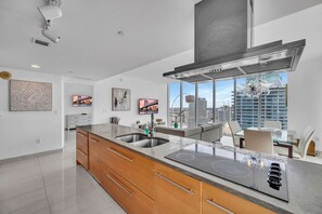 Une cuisine moderne dotée d’un grand îlot central, d’appareils électroménagers en acier inoxydable et offrant une vue sur la ville.