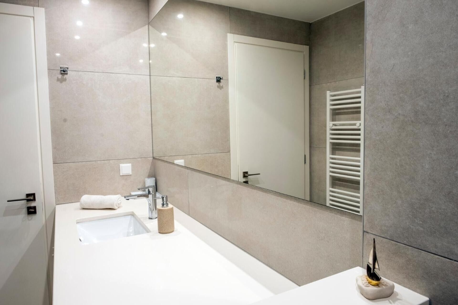 A modern bathroom with a large mirror, a towel rack, and a sink.