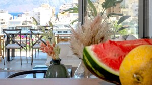Une table avec un vase rempli de plumes d’herbe des pampas, une tranche de pastèque et un vase en verre.