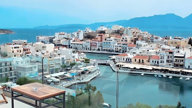 Une terrasse sur le toit avec un jacuzzi, une table et une vue sur une ville côtière, avec ses bâtiments et son port de plaisance.