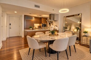 A modern kitchen with wooden cabinets, a central island, and a dining area with a marble table and chairs. - Icon Brickell - 31st Floor - Ocean View - Free Spa (Miami)