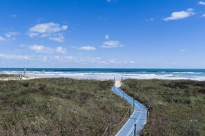 A coastal path leading to the ocean with a clear sky. - Beachfront Gem with Pool, Hot tub, Gym (South Padre Island)