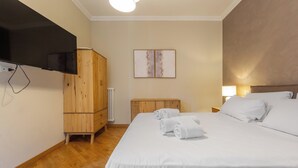 Une chambre d’hôtel avec un grand lit, une armoire en bois, un téléviseur à écran plat fixé au mur et un radiateur.