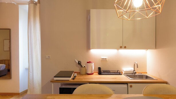 Une cuisine de taille réduite, dotée d’un plan de travail en bois, d’un évier et d’une table à manger avec des chaises.