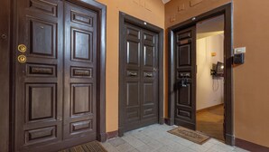 Une porte double, avec un paillasson devant, un interphone fixé au mur et une sonnette.