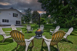 A backyard with a fire pit, white Adirondack chairs, and a house in the background. - Downtown retreat- Pilot Mt. Views- perfect for families (Pilot Mountain)