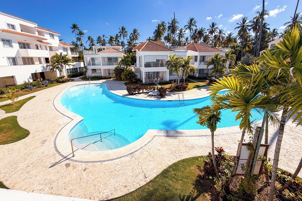 Un resort con piscina, palme e edifici moderni.