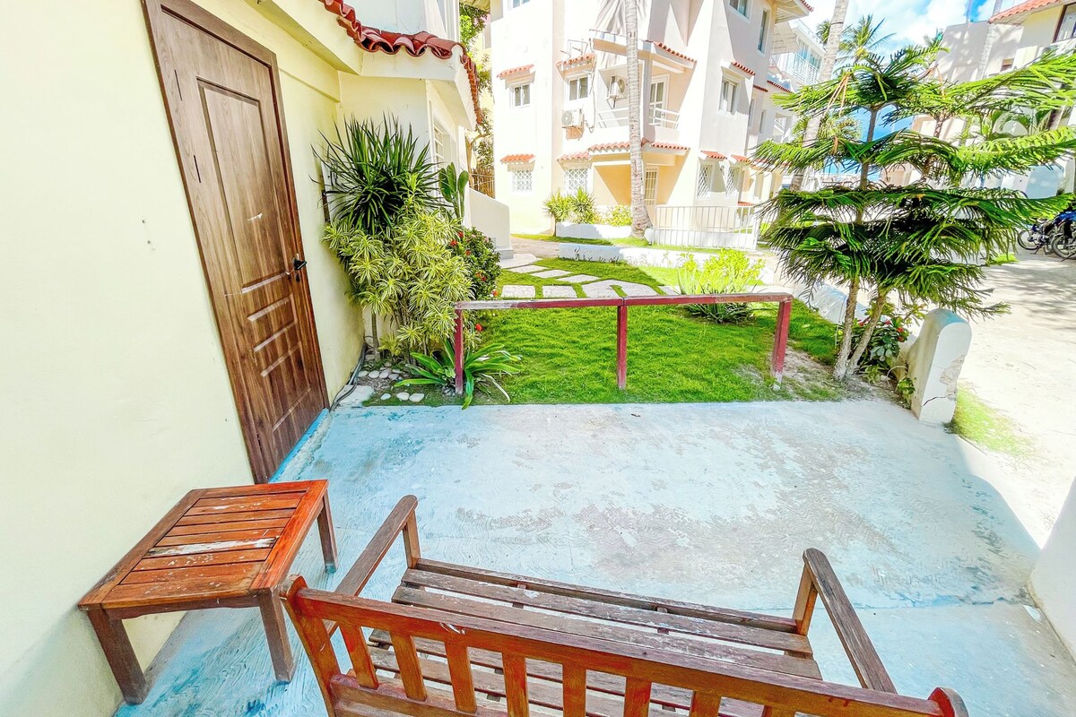 Un cortile con una panchina di legno, una porta e un tavolino.