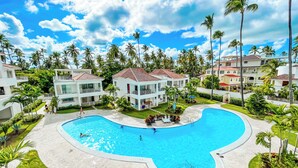 Un resort con una amplia piscina, edificios de varios pisos y palmeras.