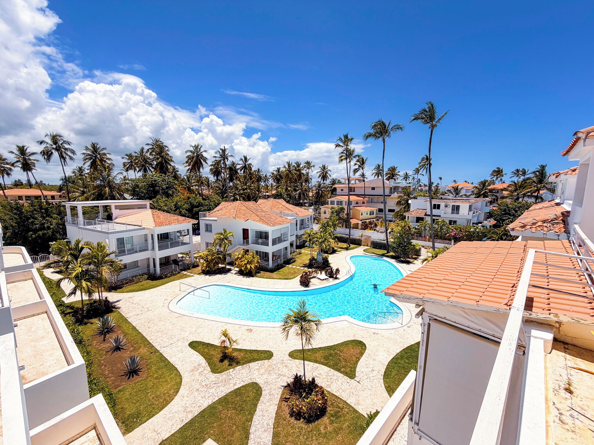 A resort with a swimming pool, palm trees, and modern buildings.