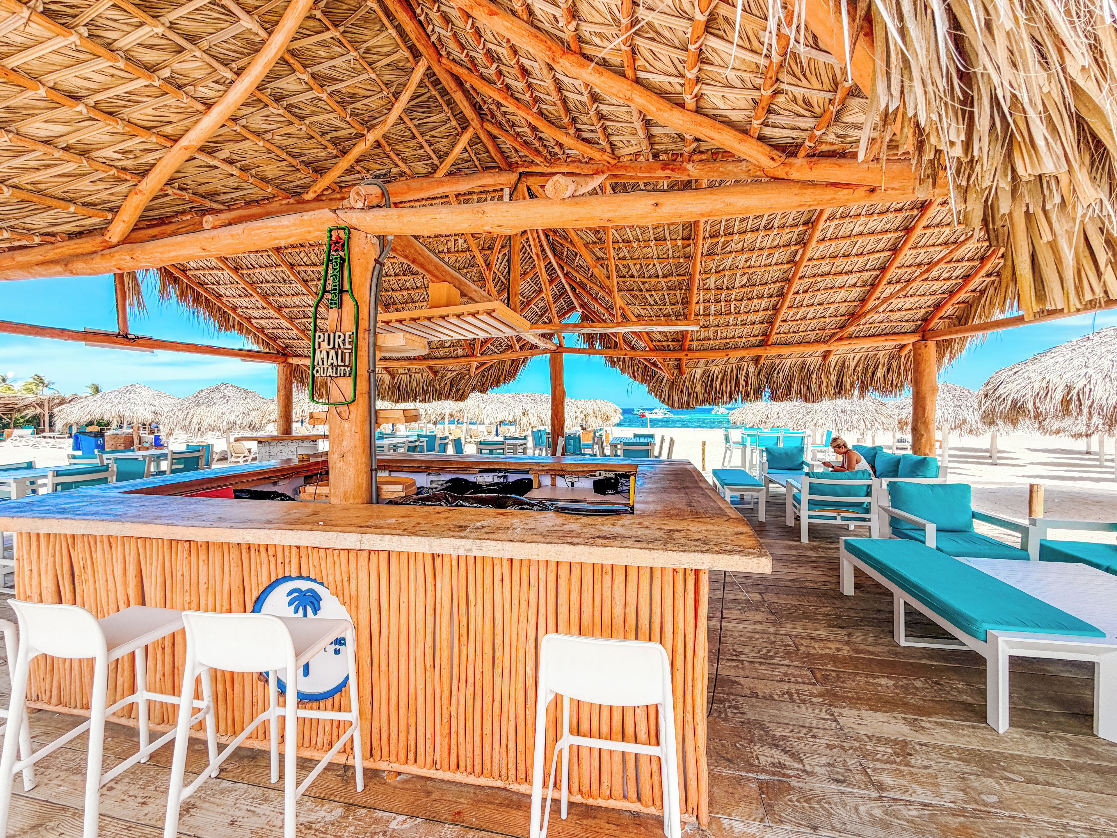 Un bar en la playa con muebles de madera y techo de paja.