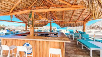 Un bar en la playa con muebles de madera y techo de paja.