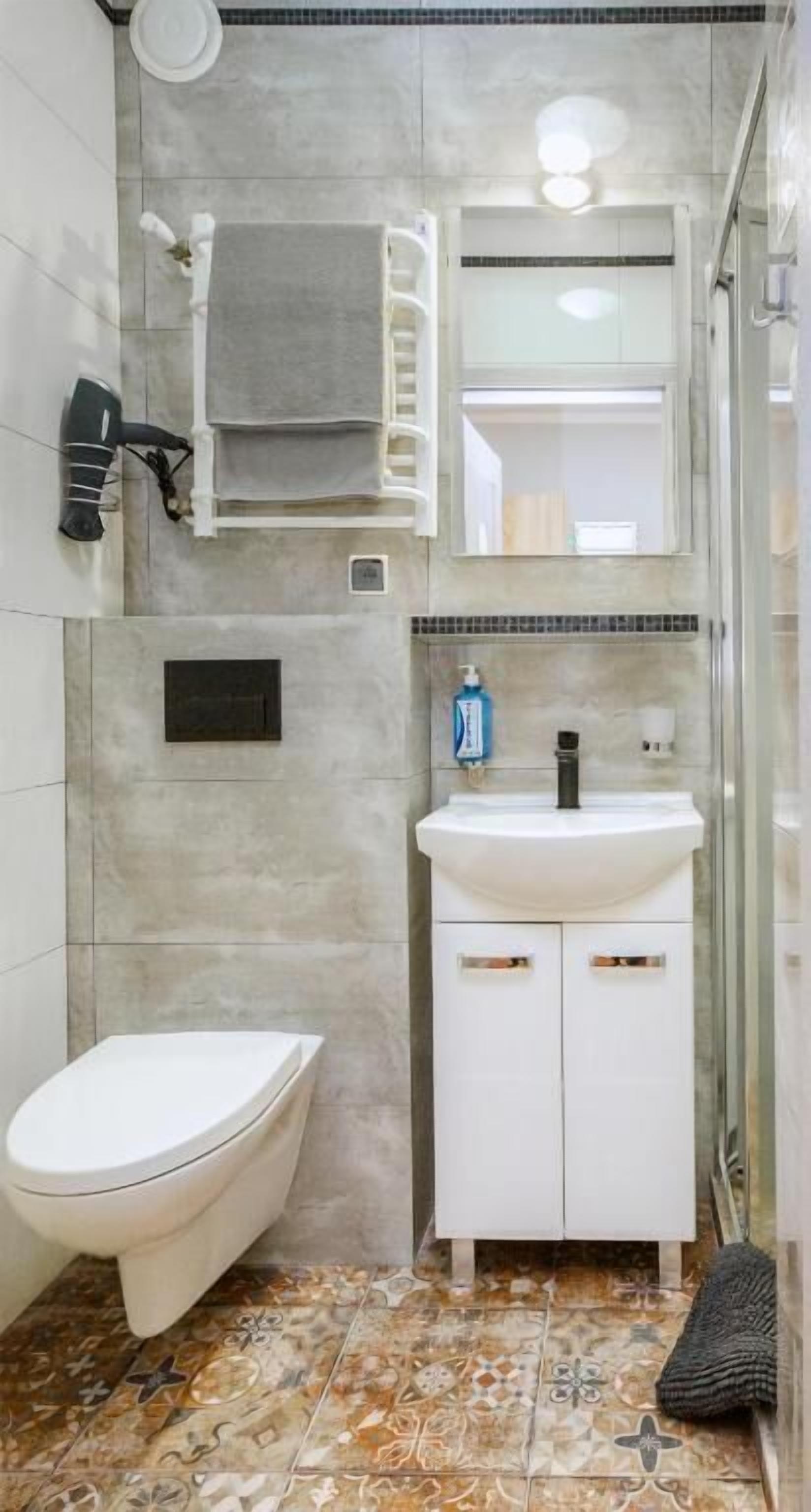 Une salle de bain comprenant des toilettes, un lavabo, un miroir et un espace douche.