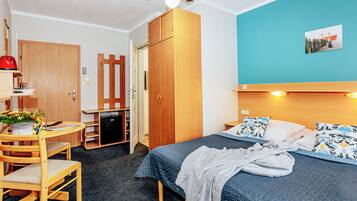 A room with a bed, a desk, a chair, a wardrobe, and a ceiling fan.