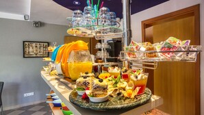 Un bufé con diferentes opciones de comida, un cuenco de frutas y utensilios para bufé.
