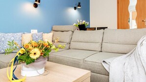 Una sala de estar con un sofá, una mesa de centro con un florero y dos lámparas de pared.