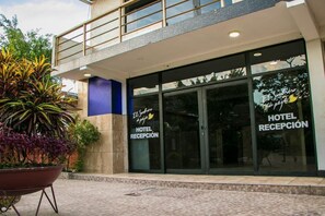 Una recepción de hotel con diseño moderno, que cuenta con fachada de vidrio y un balcón.