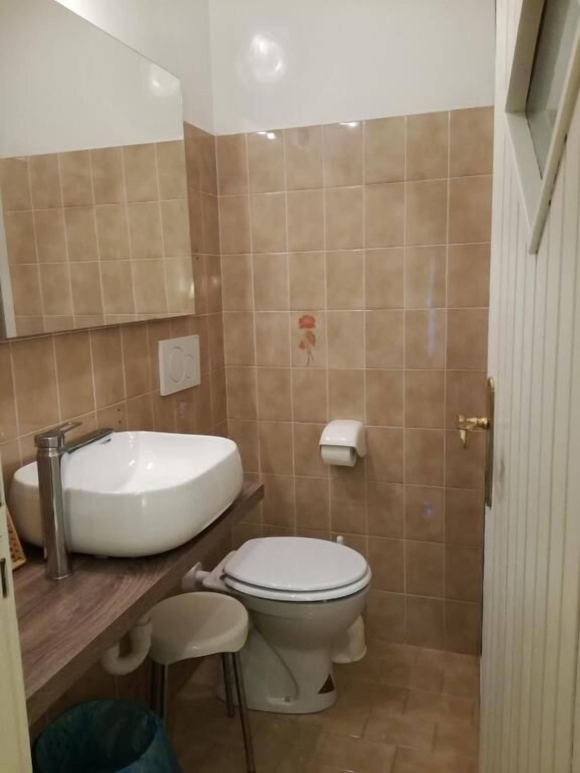 Een badkamer met een wit wastafel, toilet en spiegel.