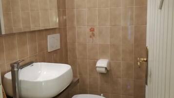 Een badkamer met een wit wastafel, toilet en spiegel.