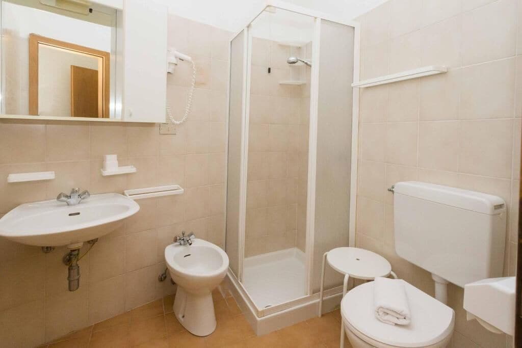 A bathroom with a sink, bidet, toilet, and a glass-enclosed shower.