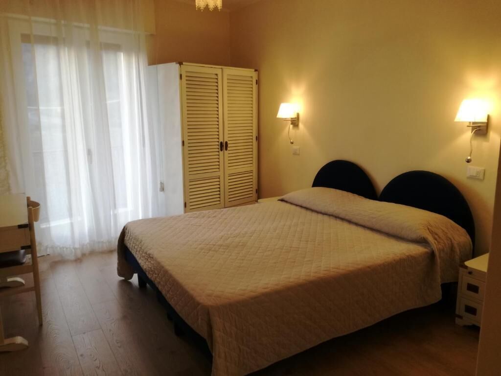 Un dormitorio con cama, armario y dos lámparas fijadas a la pared.