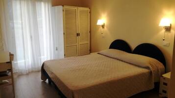 Un dormitorio con cama, armario y dos lámparas fijadas a la pared.