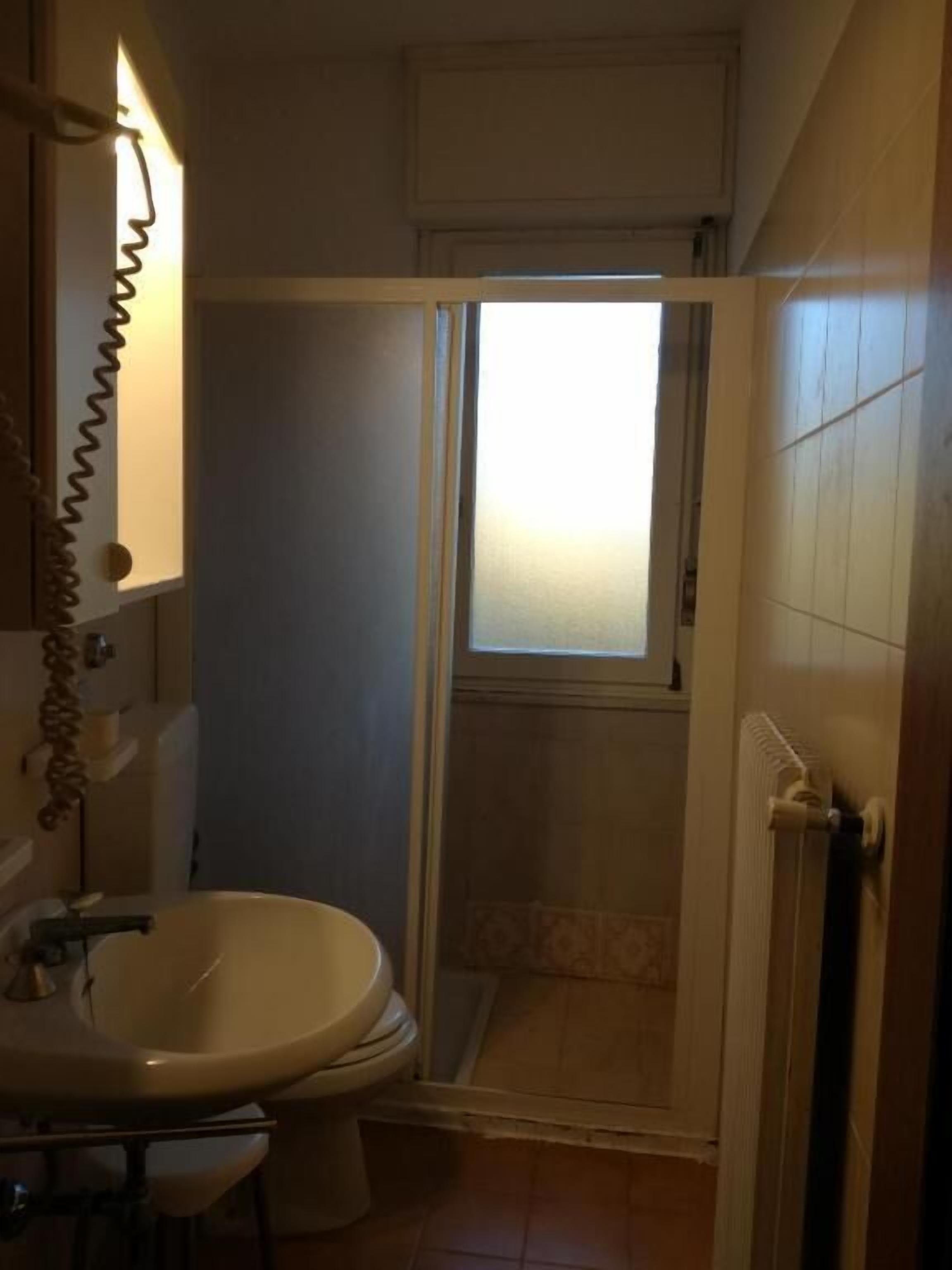 A bathroom with a toilet, sink, and shower area.