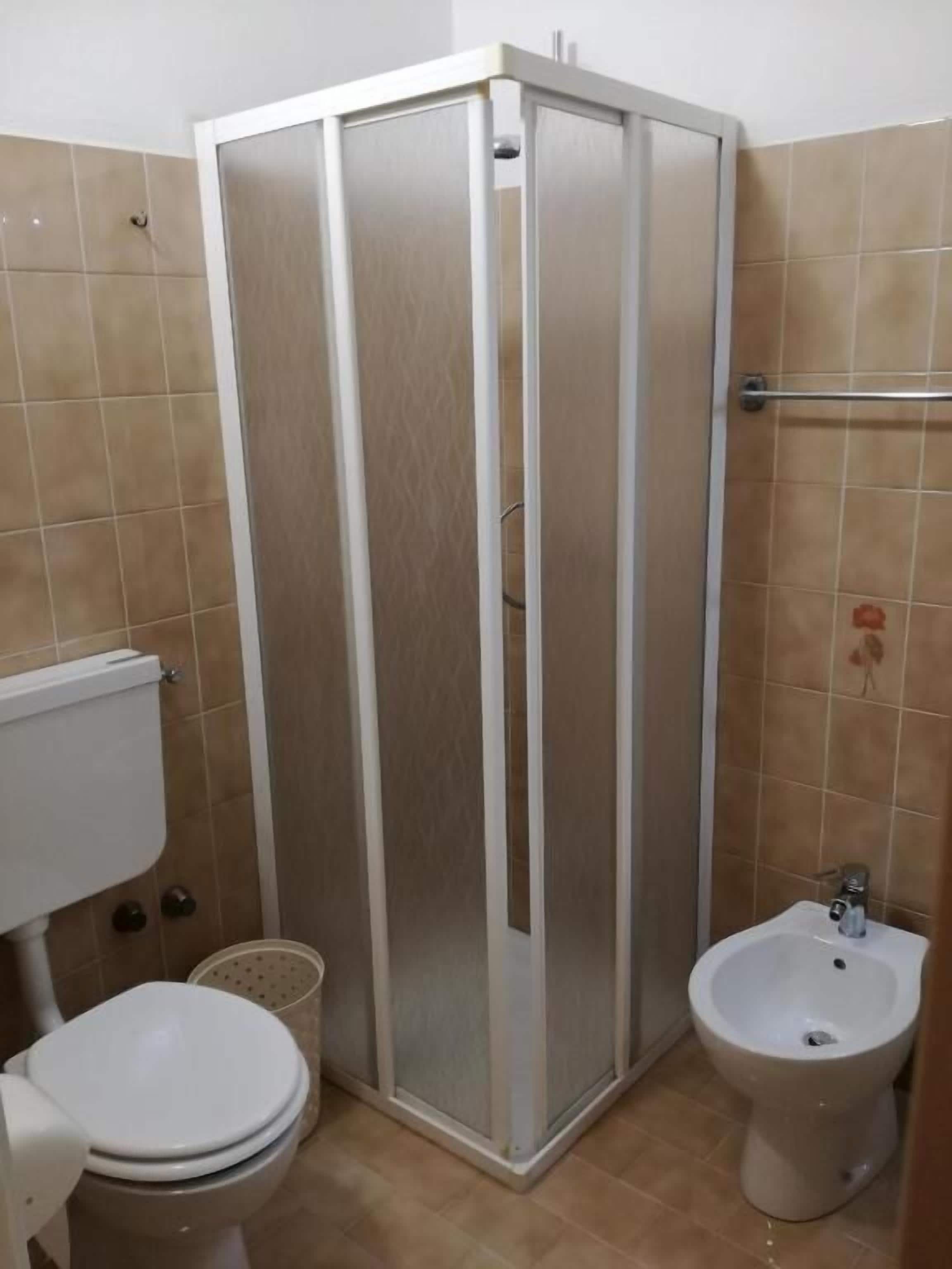 Casa de banho com sanita, bidé e cabine de duche.