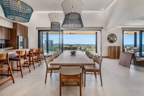 A modern dining area with a long table, wooden chairs, and hanging pendant lights. - Spacious 5-bedroom Pent-house condo with AC in stunning Tamarindo (Tamarindo)