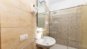 Un bagno con doccia, lavandino, asciugacapelli e specchio.