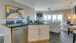 Una cucina moderna con isola centrale, mobili bianchi e un'ampia finestra vista oceano.