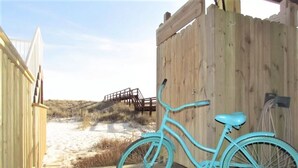 Una bicicletta color turchese parcheggiata di fronte a un recinto di legno.