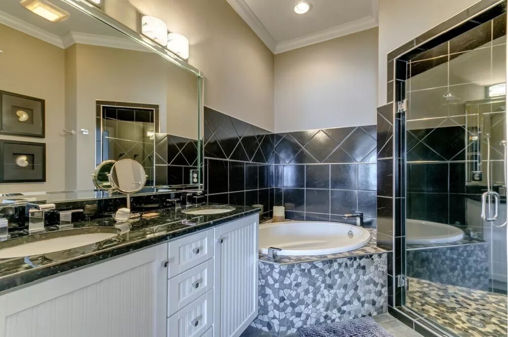 Un baño moderno con dos lavamanos, una bañera grande y una ducha a ras de suelo.